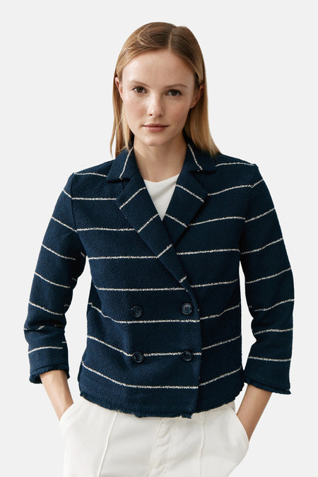 Blauwe gestreepte blazer van MORE & MORE, gedragen met een T-shirt met print en een witte broek met wijde pijpen.