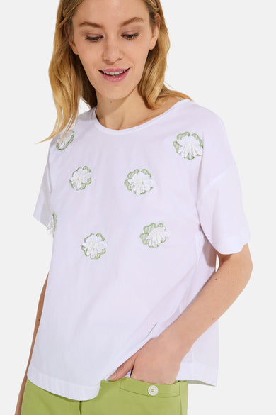 White short-sleeve t-shirt with floral embroidery and green accents, worn by model in lifestyle front view