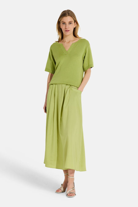 Pull vert à col en V de MORE & MORE, porté avec une jupe longue plissée assortie et des sandales à talons.
