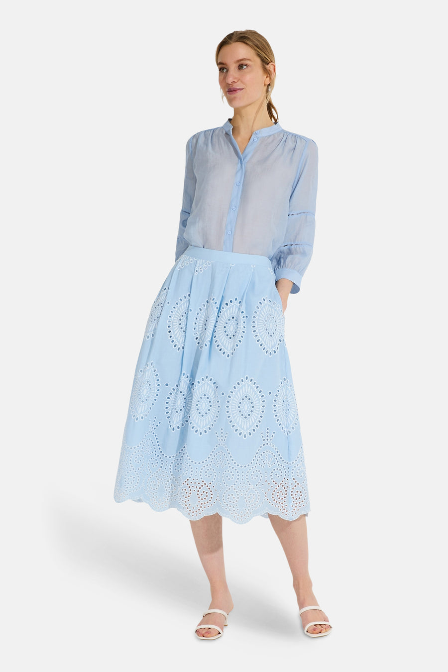 Blauwe blouse met lange mouwen van MORE & MORE, met uitgesneden details op de mouwen, gedragen met een lichtblauwe uitlopende rok.