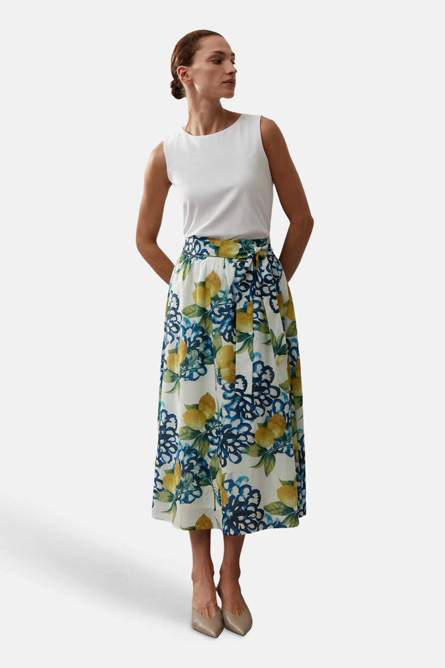 Jupe longue multicolore de More & More, à motif citron et floral bleu, portée avec un haut blanc et des chaussures nude.