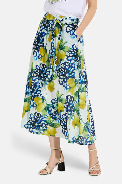 Jupe longue multicolore de MORE & MORE, à motifs de citrons et fleurs bleues, portée avec un t-shirt blanc.