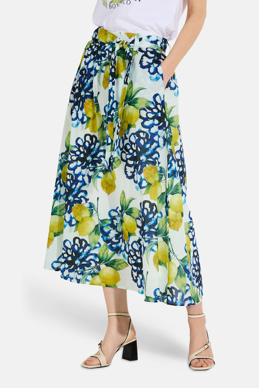 Jupe longue multicolore de MORE & MORE, à motifs de citrons et fleurs bleues, portée avec un t-shirt blanc.