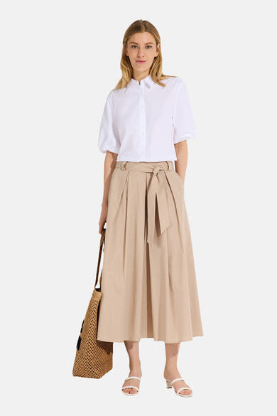 Beige schoudertas van MORE & MORE met gevlochten patroon en een vrouw met een blouse en rok.