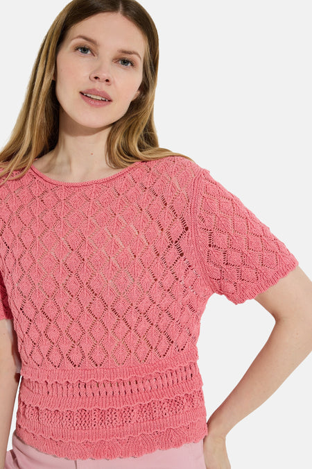 Roze trui met korte mouwen van MORE & MORE, gebreid met een ajourpatroon en ruchezoom, gedragen met een roze broek.