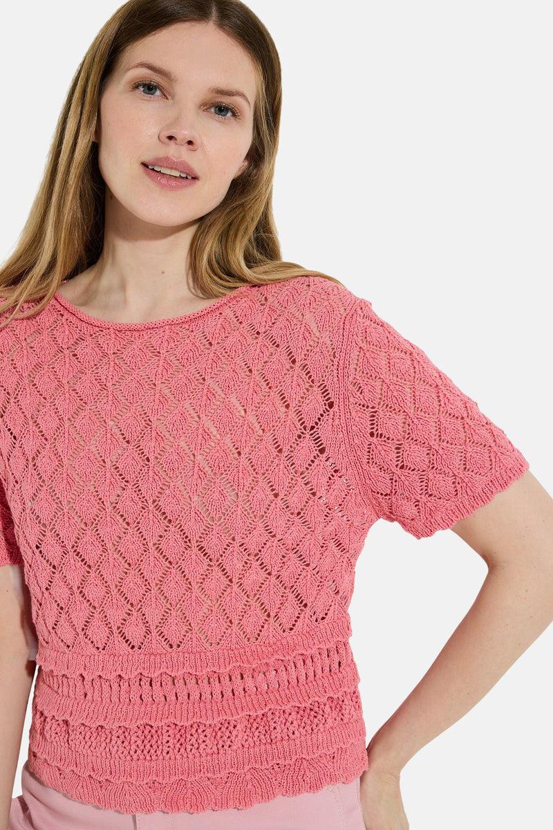 Roze trui met korte mouwen van MORE & MORE, gebreid met een ajourpatroon en ruchezoom, gedragen met een roze broek.