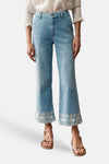 Jean droit en denim bleu clair de MORE & MORE, avec détails brodés aux ourlets et porté avec un chemisier blanc.
