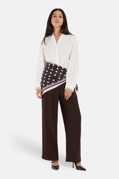 White long-sleeve blouse with lace detailing by MORE & MORE, worn with brown polka-dot wrap skirt and wide-leg trousers, full-length front view.