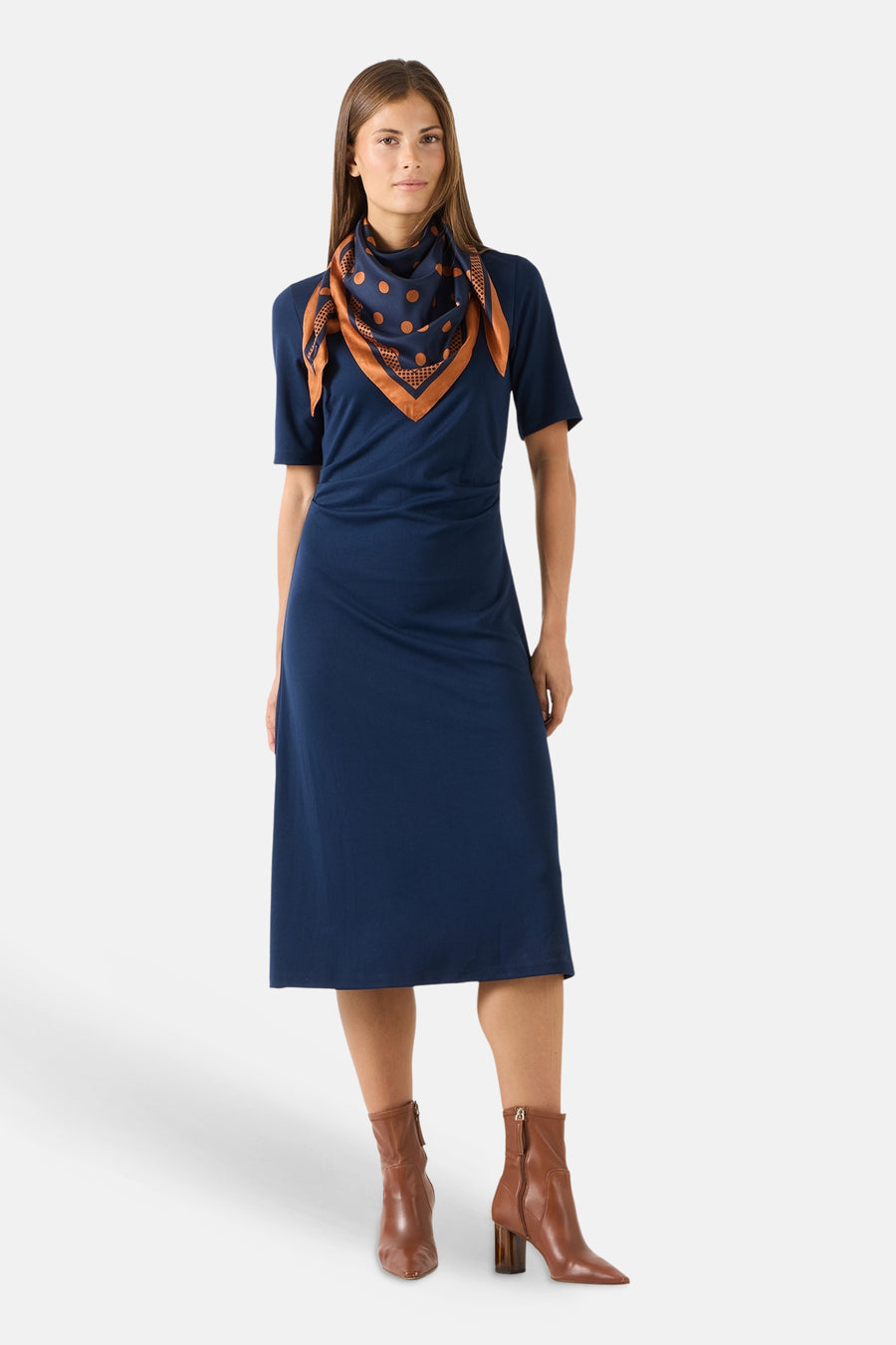 Multicolored silk foulard with navy base and orange polka dots by MORE & MORE, styled as a neck scarf on model in navy dress and brown boots, front view