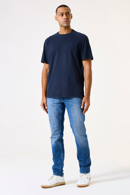 Jean tapered bleu moyen de GARCIA, porté avec un t-shirt marine et des baskets blanches.