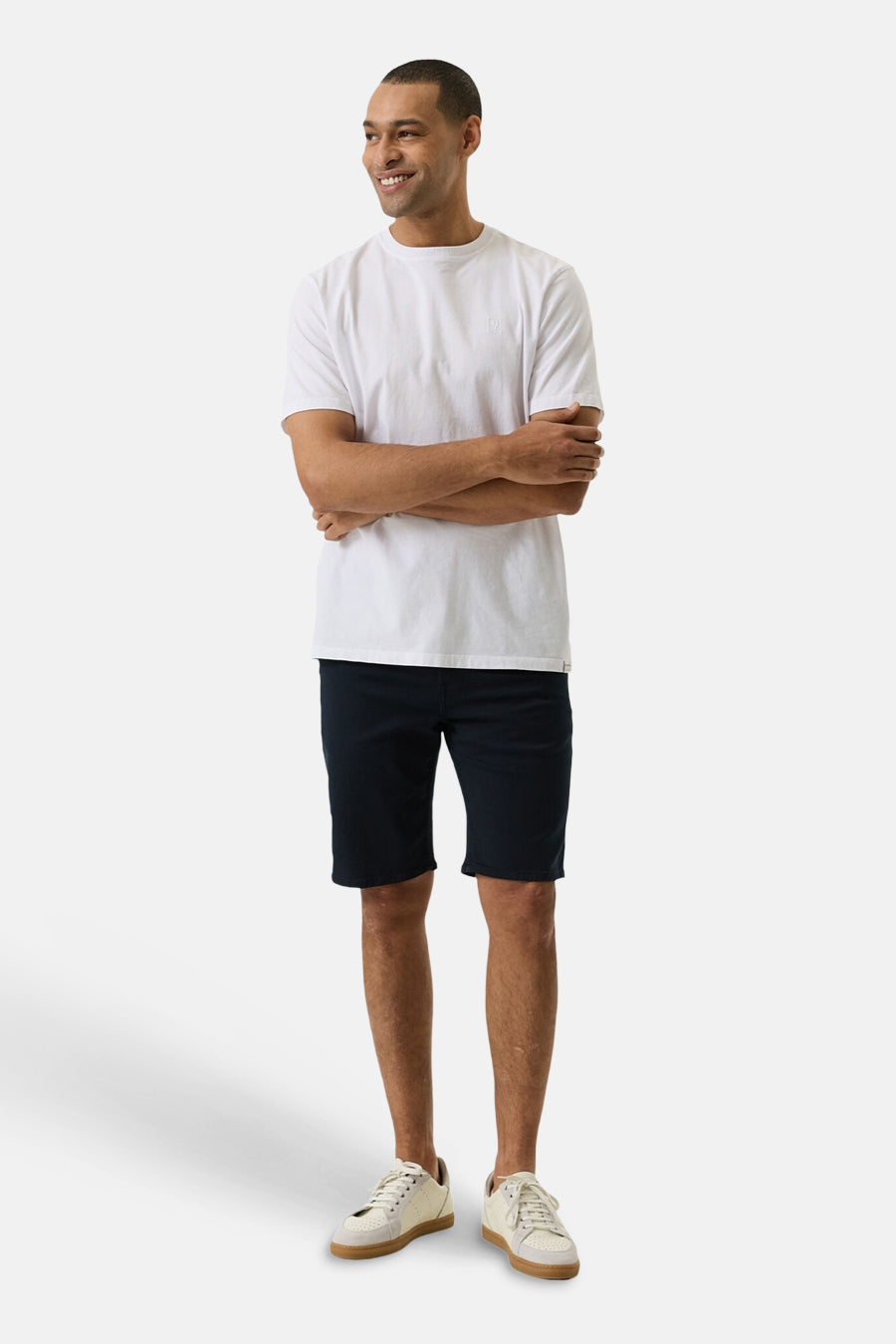 Short en jeans bleu foncé de GARCIA, porté par un homme souriant avec un t-shirt blanc et des baskets beiges.
