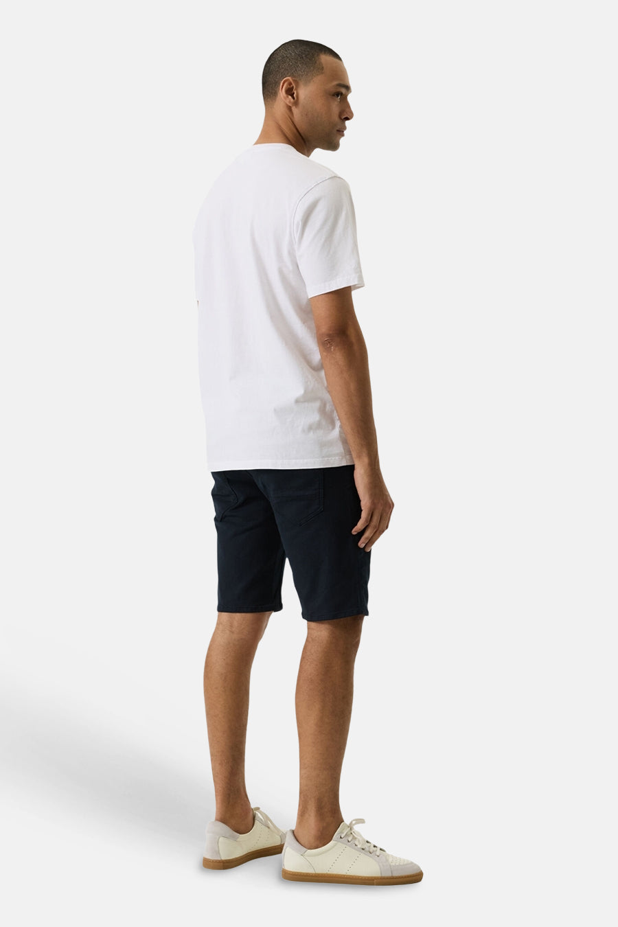 Short en jeans denim bleu foncé de GARCIA, porté par un homme en vue de côté avec un t-shirt blanc et des baskets claires.
