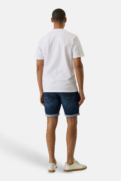 Short en jean denim bleu moyen de GARCIA, vue de dos avec ourlets retroussés, porté avec un T-shirt blanc et des baskets beiges.