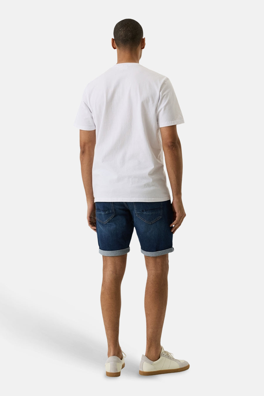 Short en jean denim bleu moyen de GARCIA, vue de dos avec ourlets retroussés, porté avec un T-shirt blanc et des baskets beiges.
