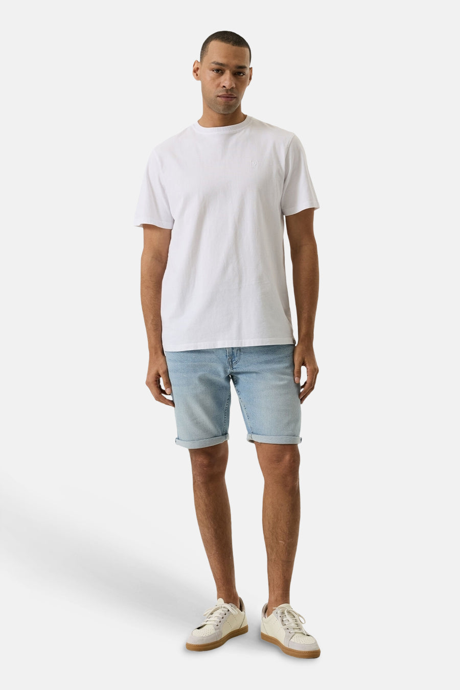 Short en jeans bleu clair en denim de GARCIA, avec ourlets retroussés, porté par un homme avec un t-shirt blanc et des baskets beiges.