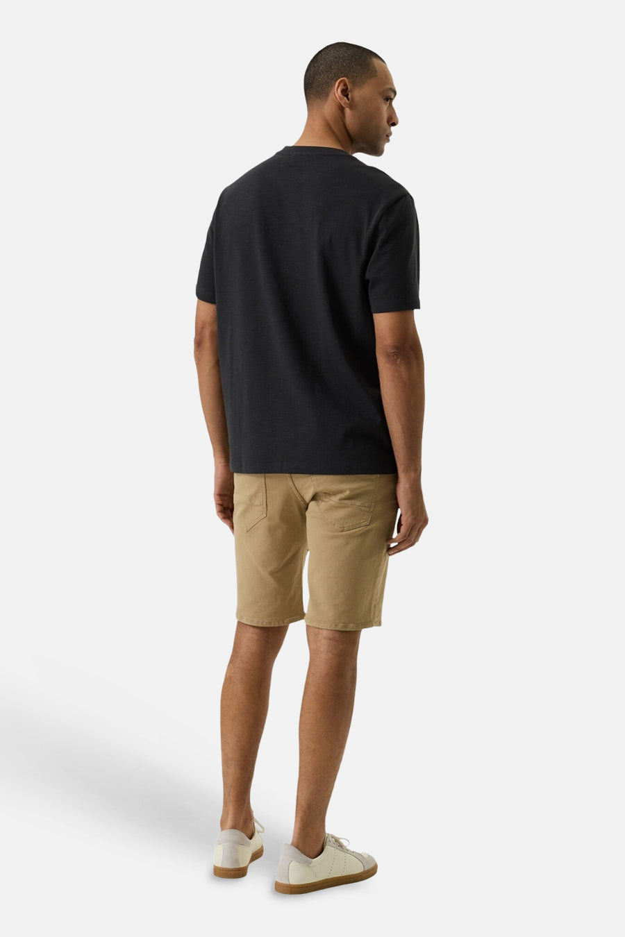 Short en jeans beige de GARCIA, porté par un homme de dos avec un t-shirt foncé et des baskets.