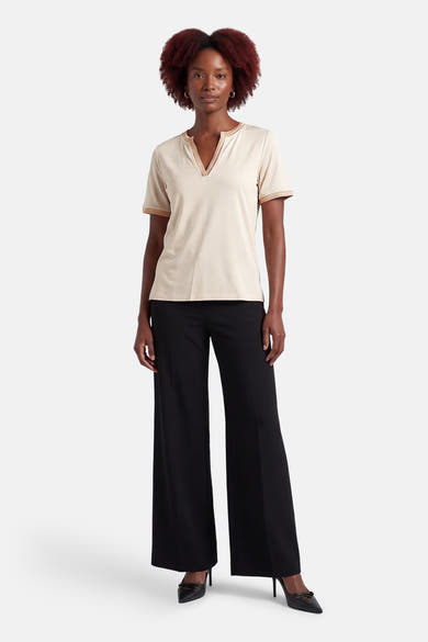 T-shirt à manches courtes beige de MORE & MORE avec garniture décorative, porté avec un pantalon noir et des talons hauts.
