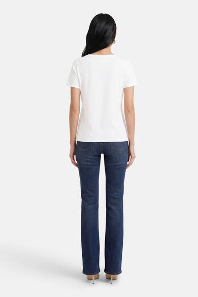 T-shirt à manches courtes blanc de MORE & MORE, porté avec un jean bleu et des talons beiges.