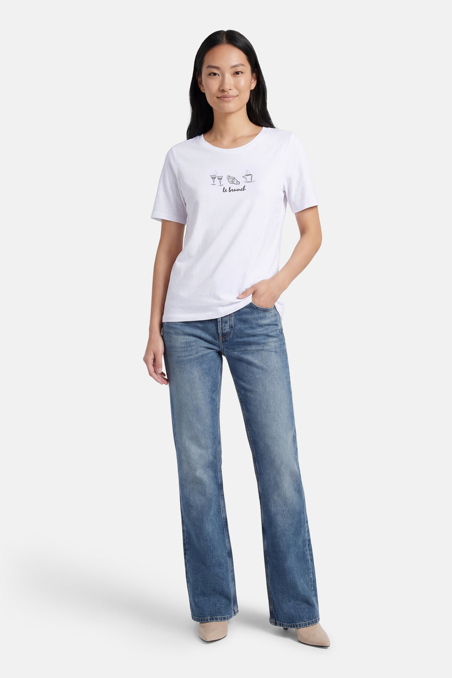 T-shirt blanc à manches courtes de MORE & MORE orné d'un motif brunch, porté avec un jean bleu et des chaussures nude.