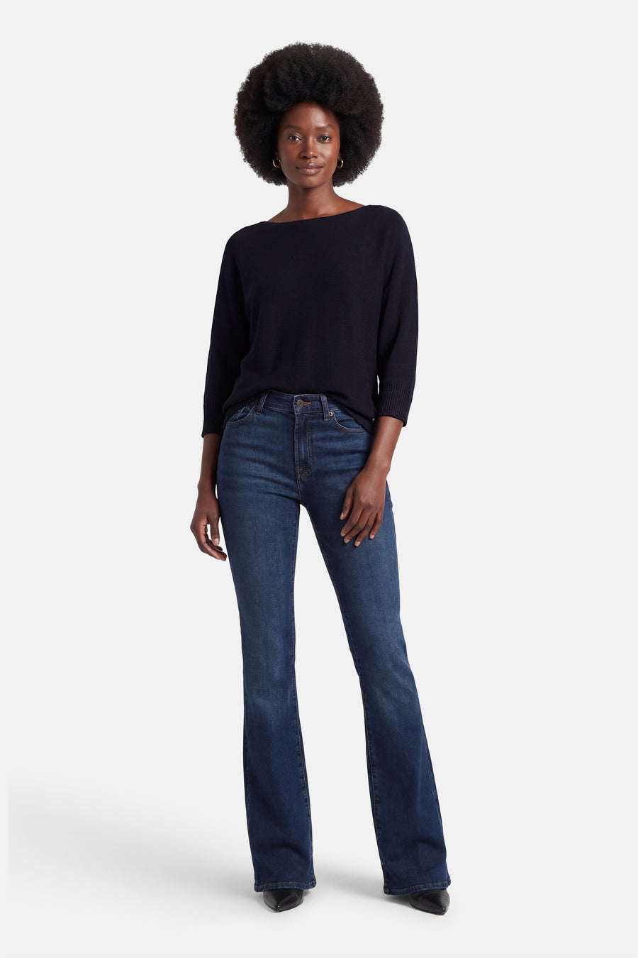 Pull à col rond bleu de MORE & MORE, porté avec un jean bootcut bleu foncé et des escarpins noirs pointus.