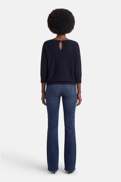 Pull à col rond bleu de MORE & MORE, avec découpe goutte d'eau au dos, porté avec un jean bleu.
