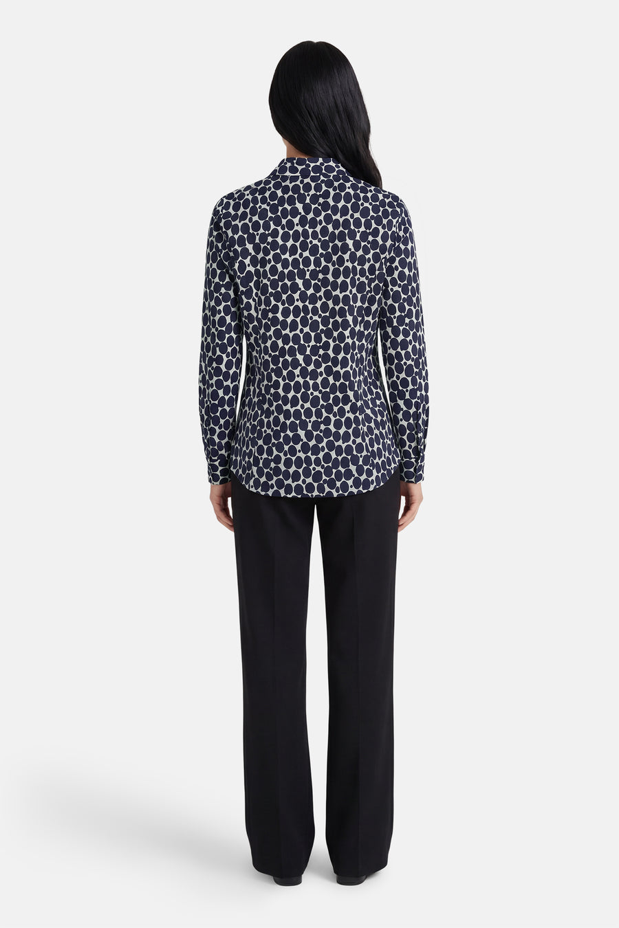 Blauwe blouse met lange mouwen van MORE & MORE met stippenpatroon, gedragen met een zwarte broek.