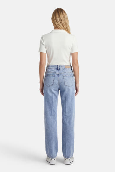 Jean droit en denim bleu clair de MORE & MORE, avec des poches arrière, porté avec un t-shirt blanc.
