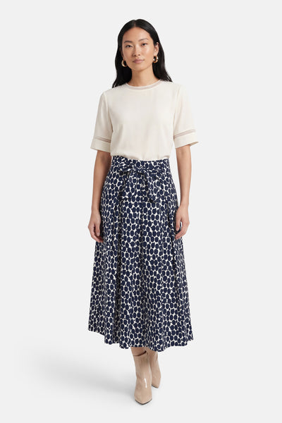 Jupe 3/4 multicolore de MORE & MORE avec motif à pois et ceinture nouée, portée avec un haut beige et des bottines.
