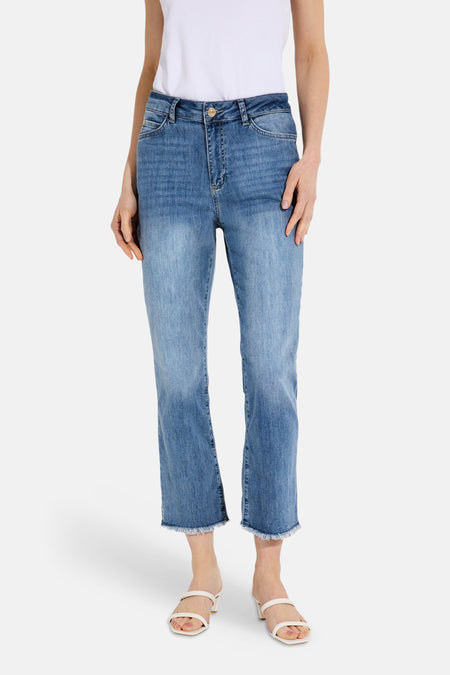 Jean droit court en denim bleu clair de MORE & MORE, avec ourlet effiloché et porté avec un haut blanc et des sandales à talons.