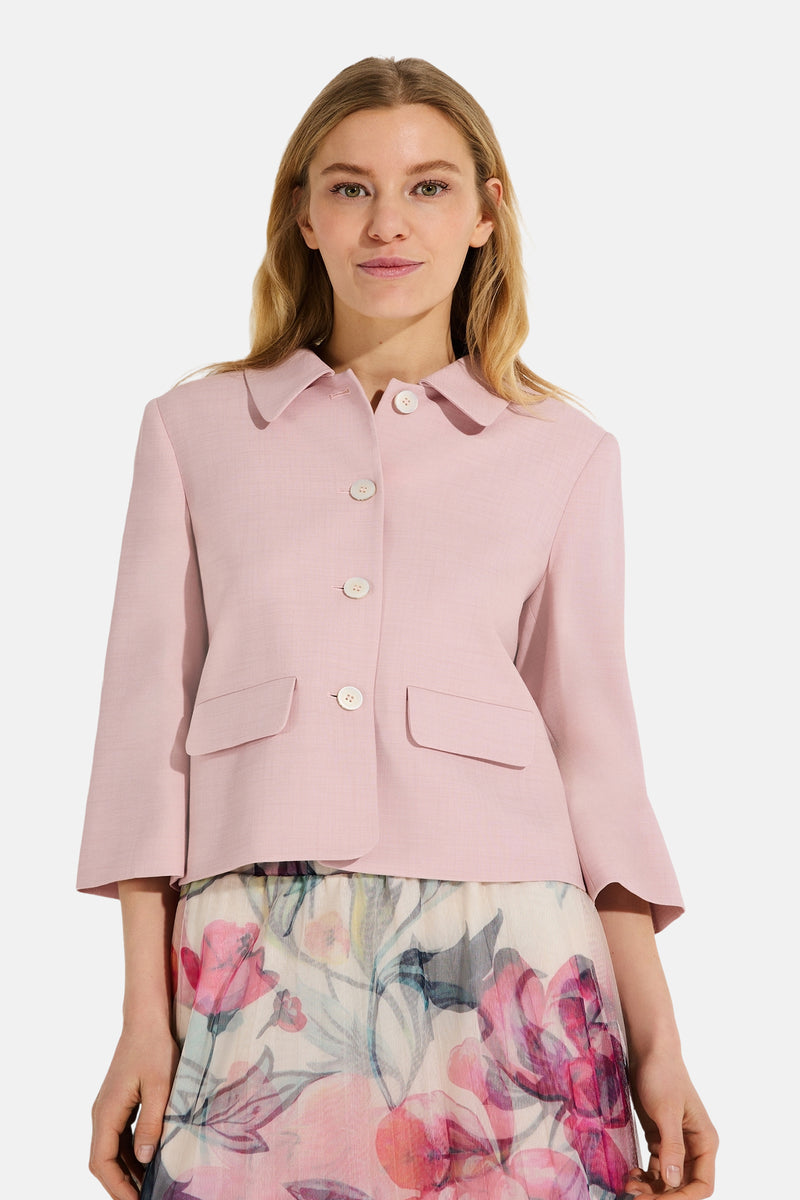 Veste courte rose de MORE & MORE, avec des poches plaquées et une jupe fleurie portée en dessous.