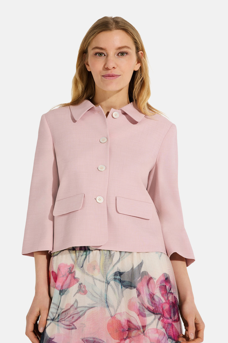 Korte roze jas van MORE & MORE met witte knopen, gedragen met een rok met bloemenprint.