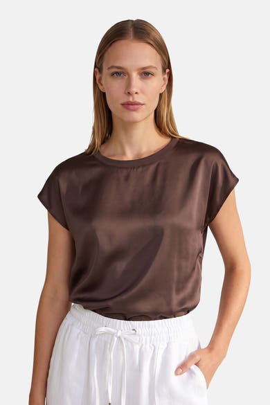 Brown satin short-sleeve top by MORE & MORE, featuring a round neckline and relaxed fit, worn with white drawstring pants in a front view.