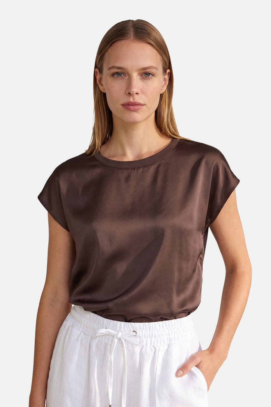 Brown satin short-sleeve top by MORE & MORE, featuring a round neckline and relaxed fit, worn with white drawstring pants in a front view.