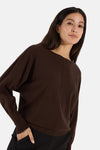 Brown round-neck sweater by MORE & MORE, featuring ribbed cuffs and hem, shown in side view on model with black pants.