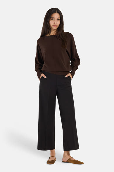 Brown round-neck sweater by MORE & MORE, featuring ribbed cuffs and hem, worn with black wide-leg pants and brown flats, front view.