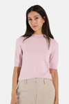 Soft pink ribbed knit turtleneck sweater by MORE & MORE, short sleeves, front view on model with beige trousers.
