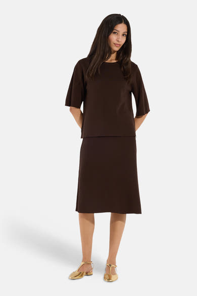 Brown round-neck sweater by MORE & MORE, featuring three-quarter sleeves and a relaxed fit, worn with matching skirt and gold sandals in a full-length front view.