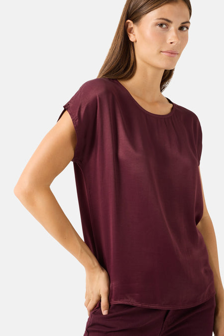 Burgundy short-sleeve chemisier by MORE & MORE, featuring a relaxed fit with rounded neckline and smooth fabric, shown in side view on model.