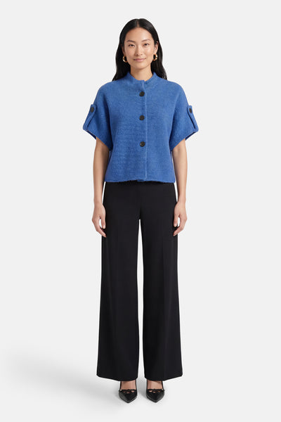Blauwe cardigan van Terra di Siena met korte mouwen en knopen, gedragen met een zwarte broek en pumps.
