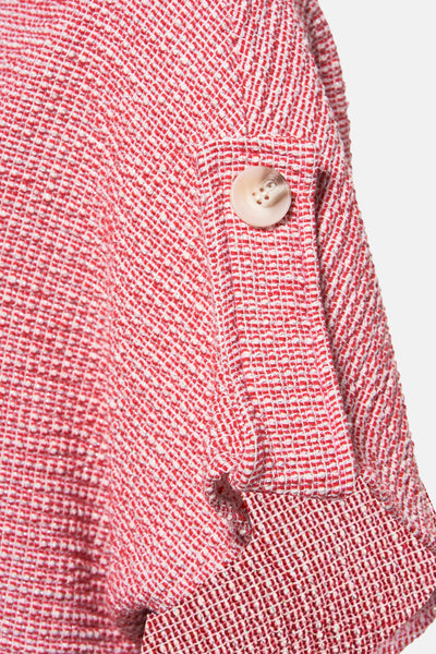 Cardigan rouge en tweed, de Terra di Siena, avec une boutonnière décorative sur la manche.
