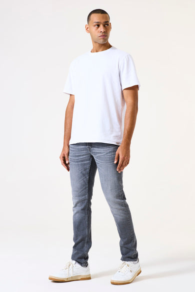 Jean slim en denim bleu moyen de GARCIA, porté avec un t-shirt blanc et des baskets blanches.