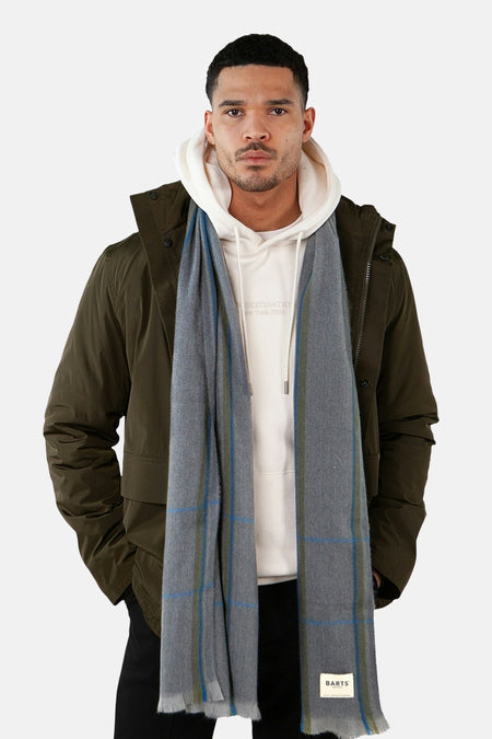 Écharpe grise à carreaux de BARTS, portée avec un sweat à capuche blanc et une veste kaki.