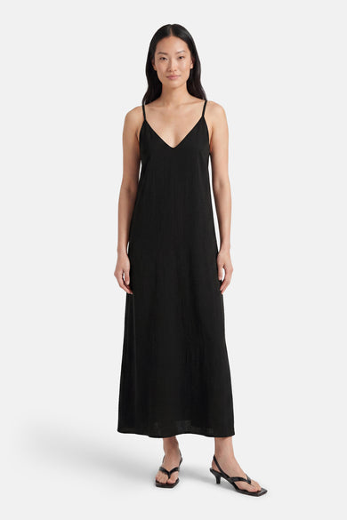 Black sleeveless maxi robe with spaghetti straps and V-neck, worn by model in front view with black heeled sandals.