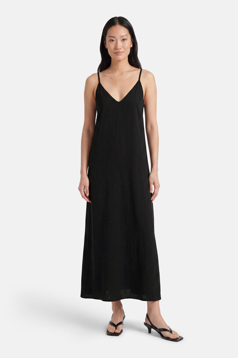 Black sleeveless maxi robe with spaghetti straps and V-neck, worn by model in front view with black heeled sandals.