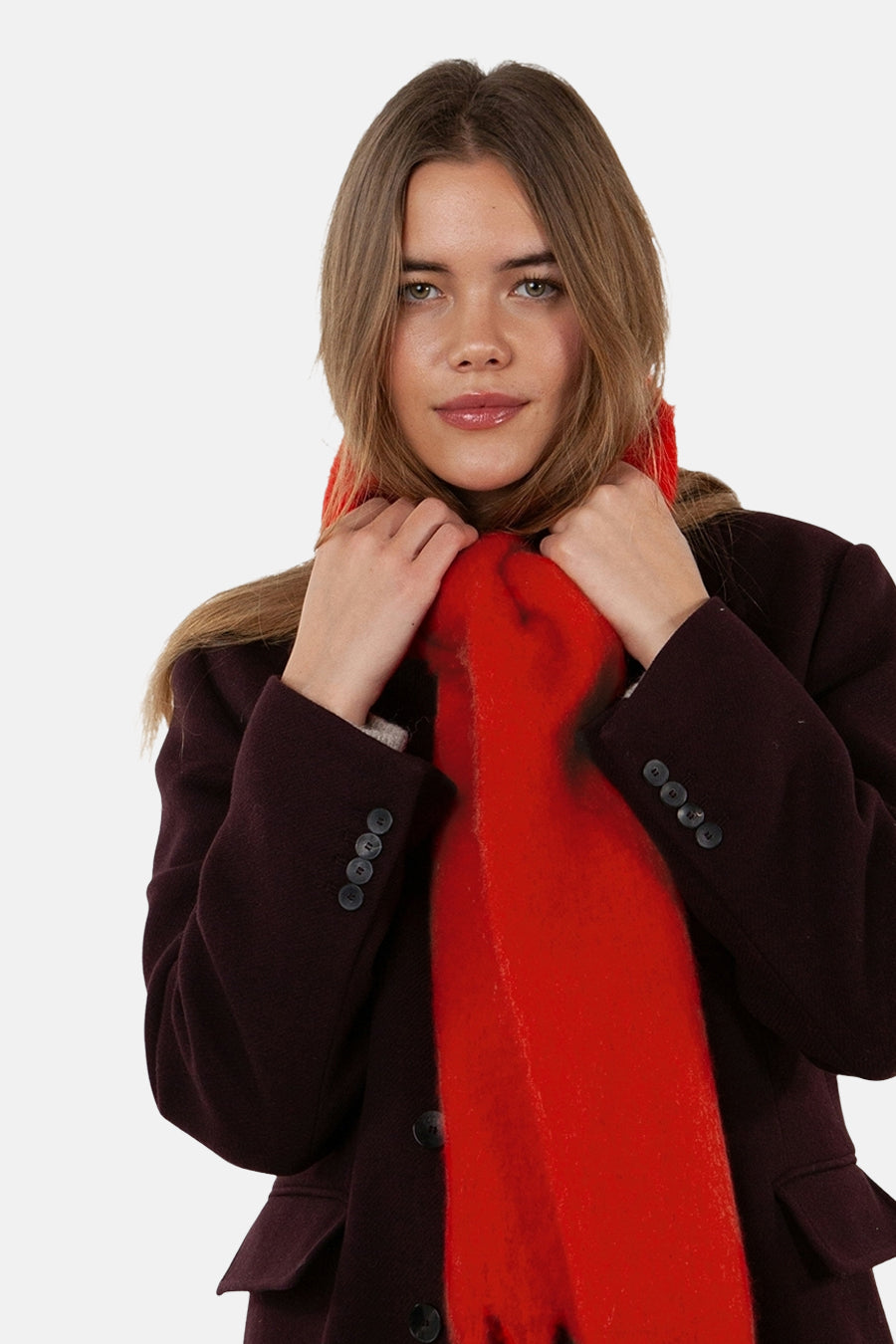 Écharpe rouge par Barts, texturée, portée avec un manteau bordeaux et des mains tenant l'écharpe.