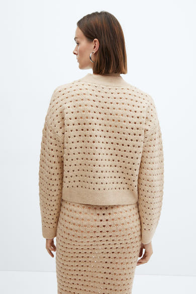 Pull beige ajouré de MANGO, porté avec une jupe assortie, vu de dos.
