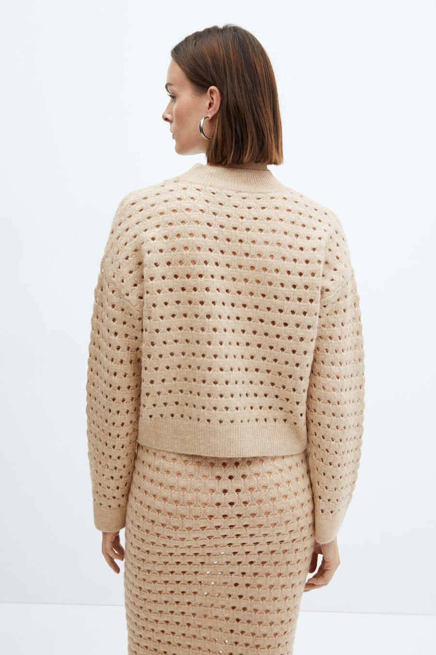 Pull beige ajouré de MANGO, porté avec une jupe assortie, vu de dos.