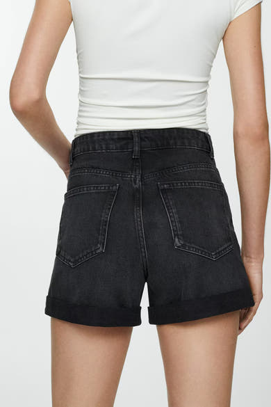 Short en denim noir de MANGO, porté avec un t-shirt blanc moulant, vue de dos.

