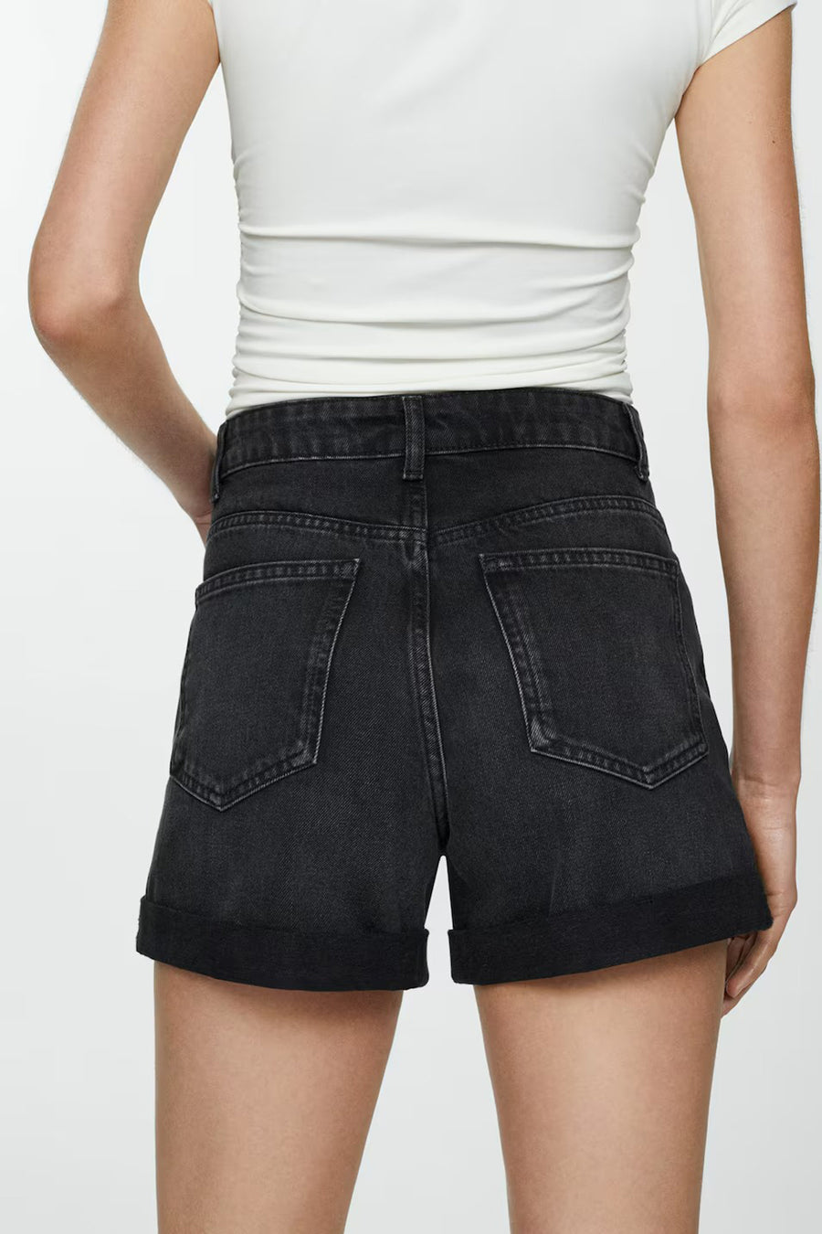 Short en denim noir de MANGO, porté avec un t-shirt blanc moulant, vue de dos.
