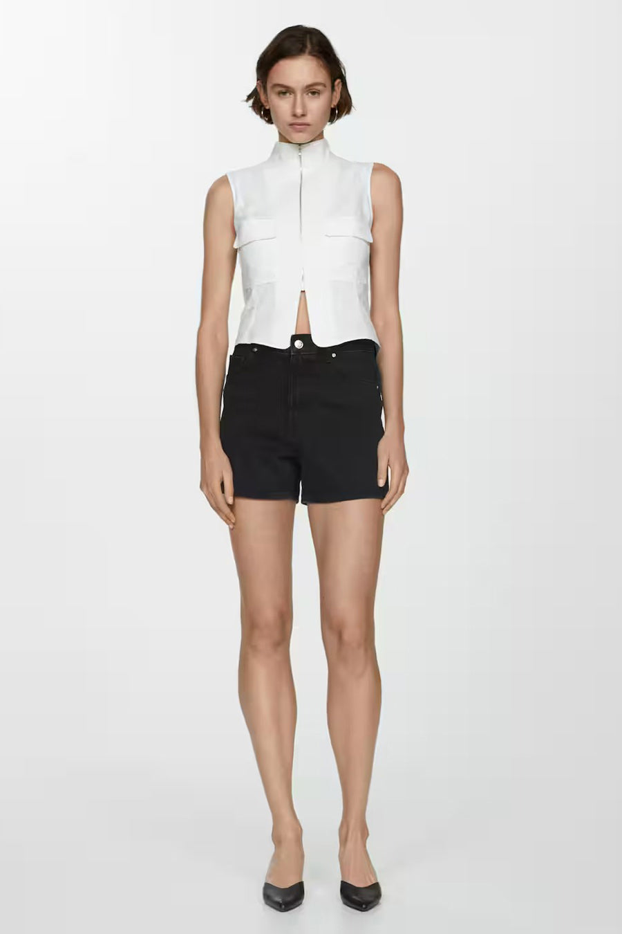 Zwarte MANGO short, gedragen met een witte top en zwarte pumps.